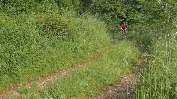 Man riding a bike on field path alt
