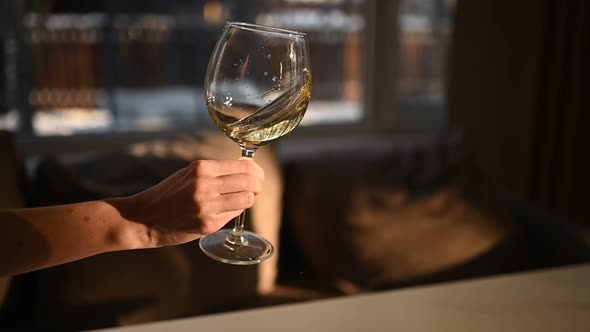 Waving White Wine in Glass on Female Hand