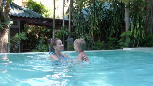 Young Pretty Woman with Her Son Enjoying at a Pool Indoors
