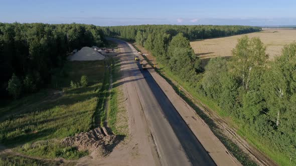 Road roller doing repair and paving of road amoung the fields alt