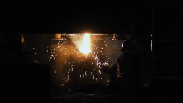 Refining the Heat: Foundry Worker Adds Flux to Industrial Furnace alt