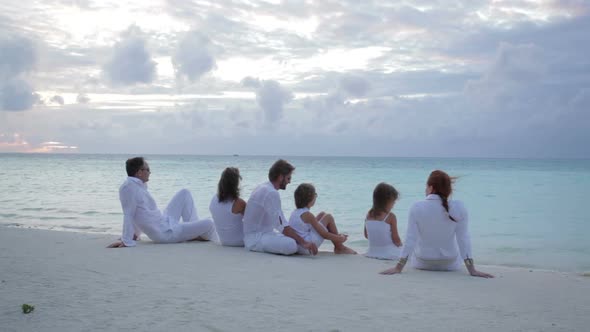 People in White Sitting on Beach