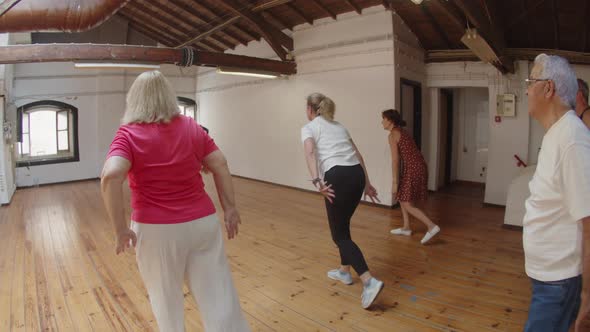 Long Shot of Focused Senior Men and Women Dancing in Ballroom alt