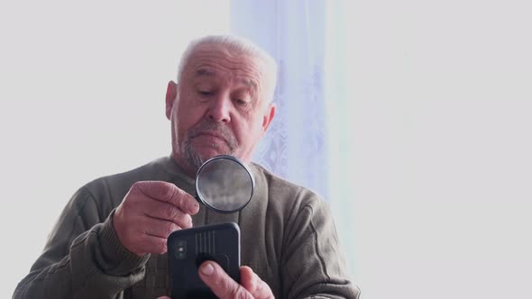 Senior Grayhaired Grandfather Reads Through a Magnifying Glass alt