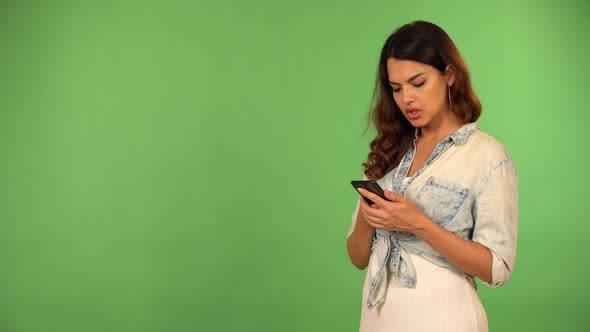 A Young Beautiful Caucasian Woman Works on a Smartphone and Acts Angry  Green Screen Background