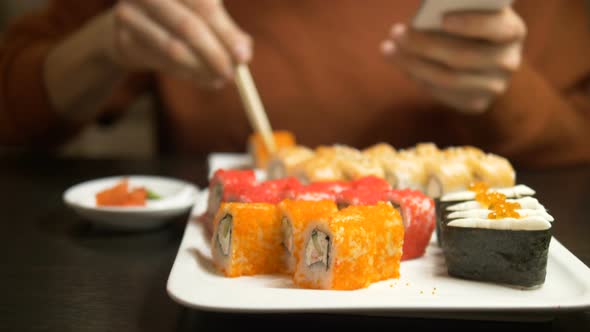 Man Chatting Online Eats Sushi Roll Covered with Caviar alt