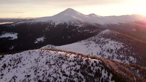 Aerial Revealing Shot of Summit Covered in Snow at Sunrise alt