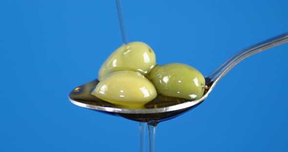 The Olives Are in a Spoon of Pouring Olive Oil. alt