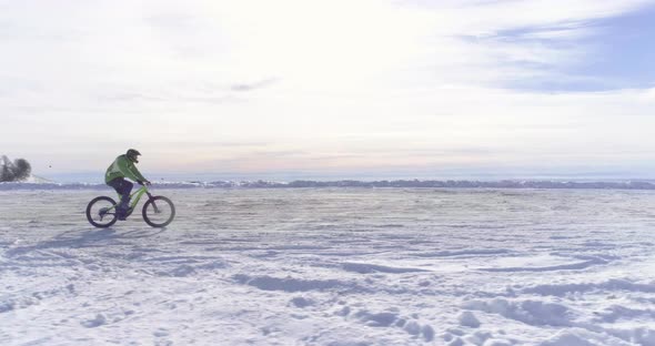 Side Aerial Over Biker Man Cycling on Snowy Path During Winter with Mtb Ebike alt