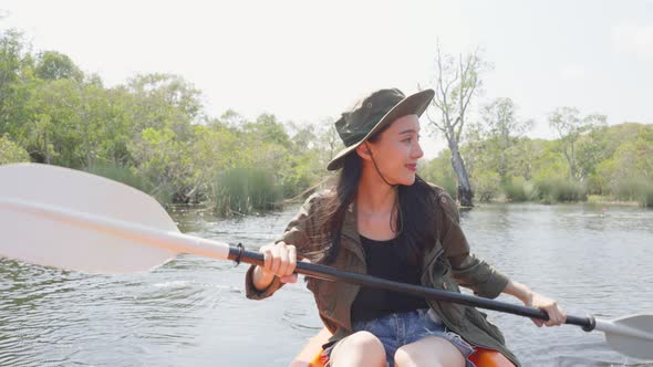 Asian young attractive tourist woman rowing kayak alone in forest lake. alt