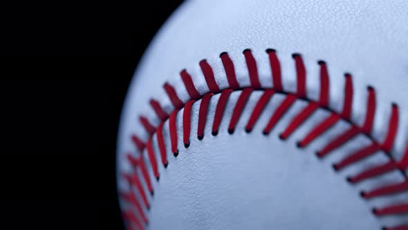 Closeup on professional white leather baseball ball on a dark background. alt
