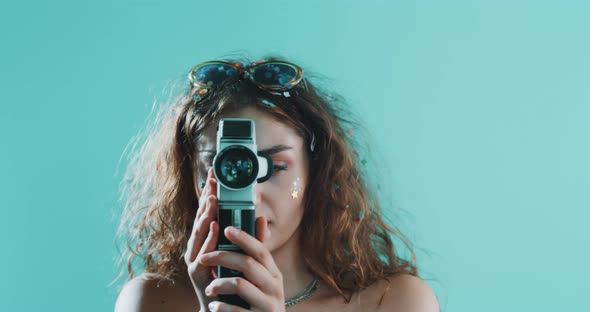 Girl covered in confetti holding a vintage camera alt