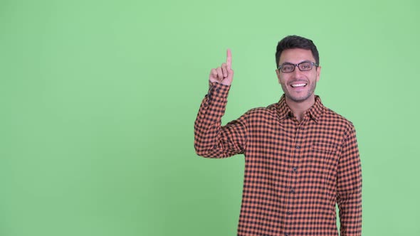 Happy Young Hispanic Hipster Man Pointing Up and Giving Thumbs Up alt