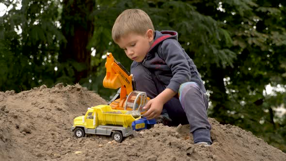 Child Playing Excavator and Dump Truck in Park, Outdoor. Little Builder Loads Sand, Soil, Ground on
