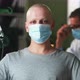 Bald Man in Mask Looking at Camera During Chemotherapy