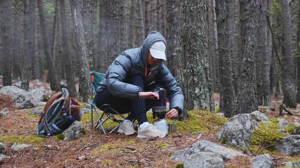 Woman in Forest Camping Boils Tea in a Gas Burner and Pours It Into a Mug
