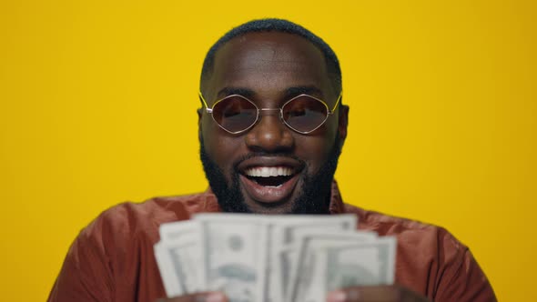 Portrait of Happy African American Man Counting Money on Yellow Background alt