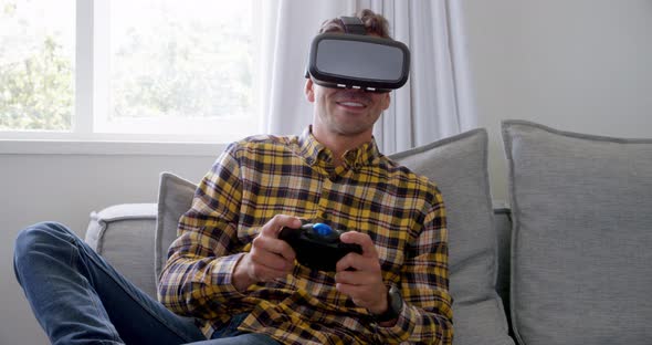 Young man using virtual reality headset and playing video game at home 