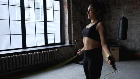 Active young Indian woman jumping with skipping rope training in gym, Girl Dressed in Sportswear alt