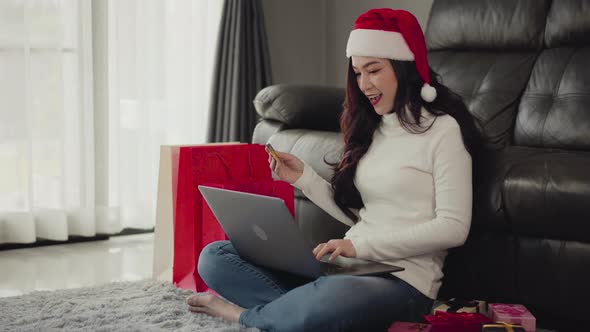woman in santa hat shopping online for Christmas gift with laptop in the living room