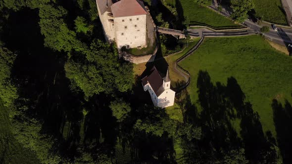 Top View Of The Lush Green Trees And The Small Church Beside Kaprun Castle In Salzburg, Austria. aer alt