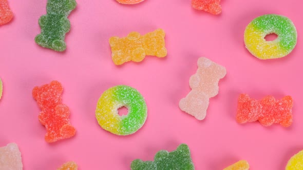 Rotating Multicolored Gummy Bears and Rings on a Pink Background the Concept of a Birthday Holiday