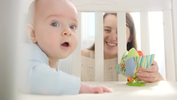 Little Baby Crawling in Cradle and Reaching for Colorful Toy alt
