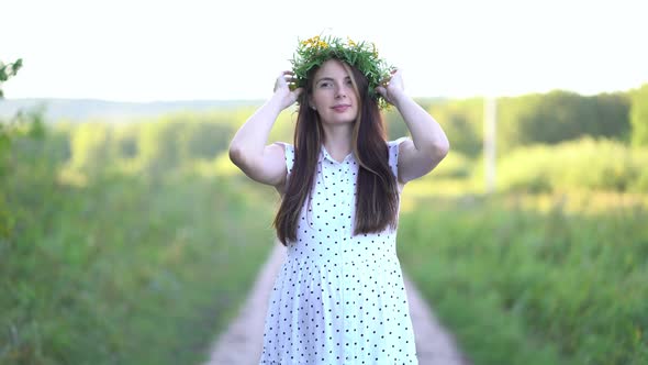 Pregnant Woman with a Wreath on Her Head Walks Outdoors
