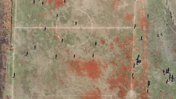 Aerial View of Rough Soccer Pitch with Players