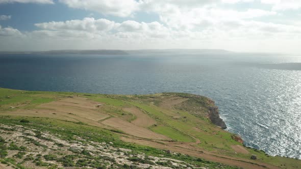 AERIAL: Steep Ta Cenc Cliffs Being Washed by Blue Mediterranean Sea alt