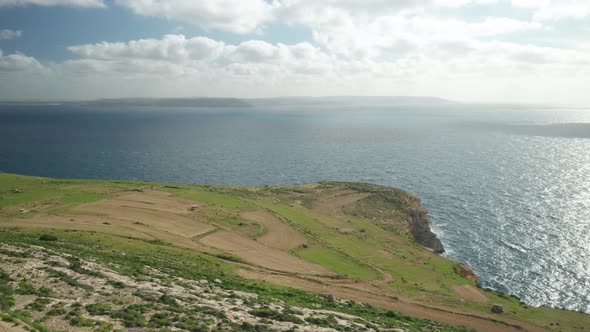 AERIAL: Steep Ta Cenc Cliffs Being Washed by Blue Mediterranean Sea