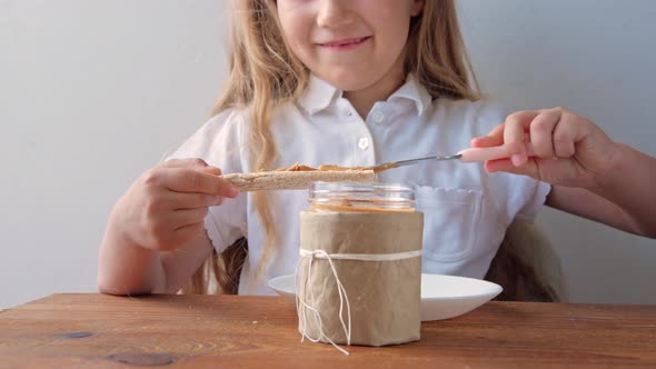 Child eating crispbread with peanut butter sitting at table home kitchen superfood vegan meal
