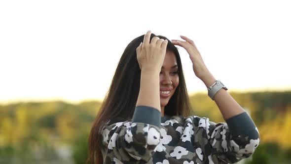 Seductive Model with Perfect Bronze Skin After Salon Touching Hair and Smiling. alt