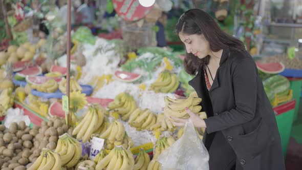 Young attractive woman shopping at the greengrocer choosing onion alt
