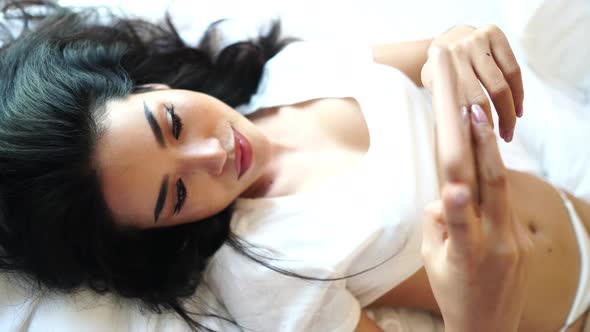 Beautiful Sexy Asian Woman in Lingerie at Bed Texting on Smartphone High Angle alt
