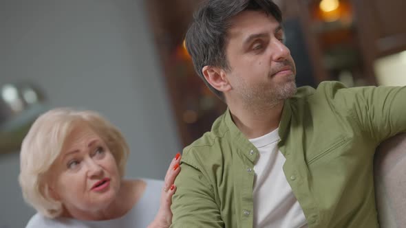 Angle View of Stressed Troubled Angry Man Talking As Senior Woman Calming Down with Worried Facial alt