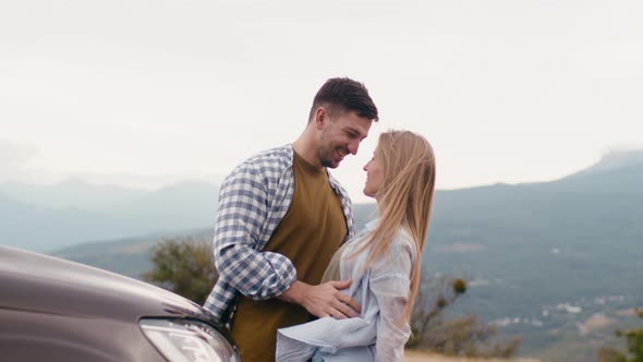 Young Traveler Couple on Road Trip in Mountains Standing Near Car