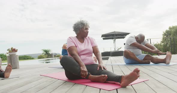 Senior diverse people practicing yoga in garden at retirement home alt