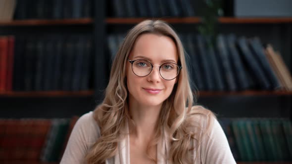 Closeup Portrait Beautiful Blonde Curly Woman Eyeglasses Smiling Posing Library Bookshelf Interior alt