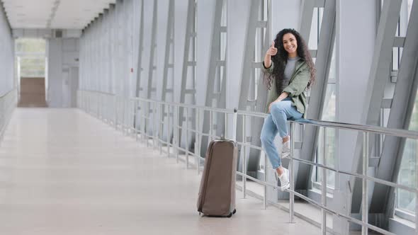 Beautiful Young Hispanic Woman Traveler Happy Girl Female Student Tourist with Suitcase Sitting in alt