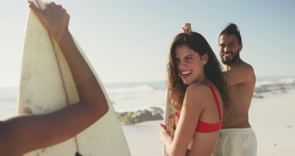 Friends holding their surfboards behind the sea alt