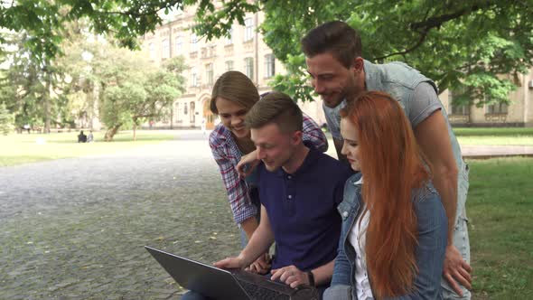 Four Students Laugh at What They See on Laptop on Campus alt