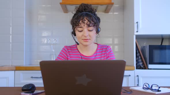 Call center operator woman workin at home during lockdown with headset and notebook computer in 4k alt
