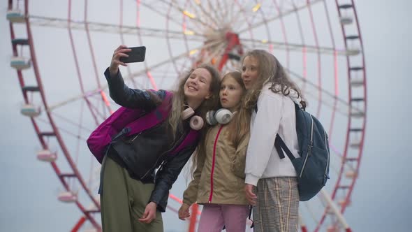 Three Joyful School Girlfriends Take Selfie Photo in Amusement Park