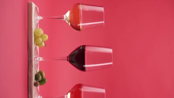Vertical video, 3 glasses of wine: white, red and rose wine, grapes and olives on a stand alt