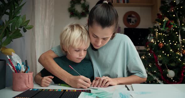 Cheerful Family Woman and Child Boy Drawing Together on Christmas Holidays