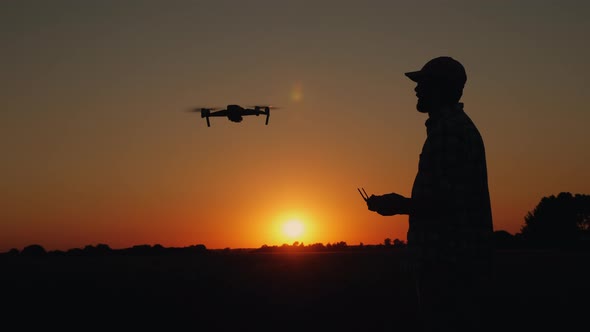 Silhouette of a Man Controlling a Drone at Sunset alt