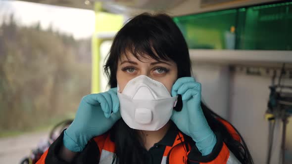 Young Female Emergency Doctor Takes Off Medical Respirator Inside an Emergency Vehicle alt