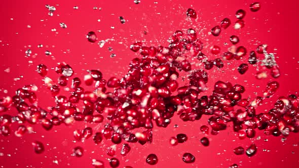 Super Slow Motion Shot of Fresh Pomegranate Seeds and Water Side Collision on Red at 1000Fps alt