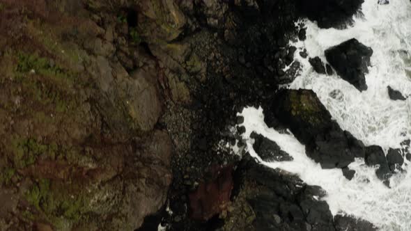 Drone overhead of the ocean waves crashing along the coast tilt up  to the Cornwall setting using in alt